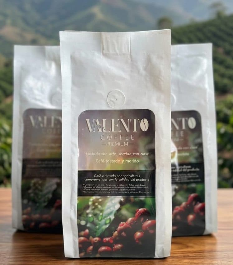 Tres bolsas blancas de café ValenTo Coffee Premium con las montañas cafeteras de fondo